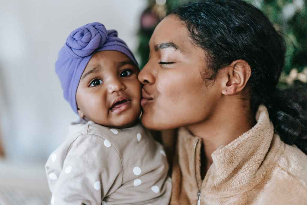 loving black mother kissing little daughter with mouth opened